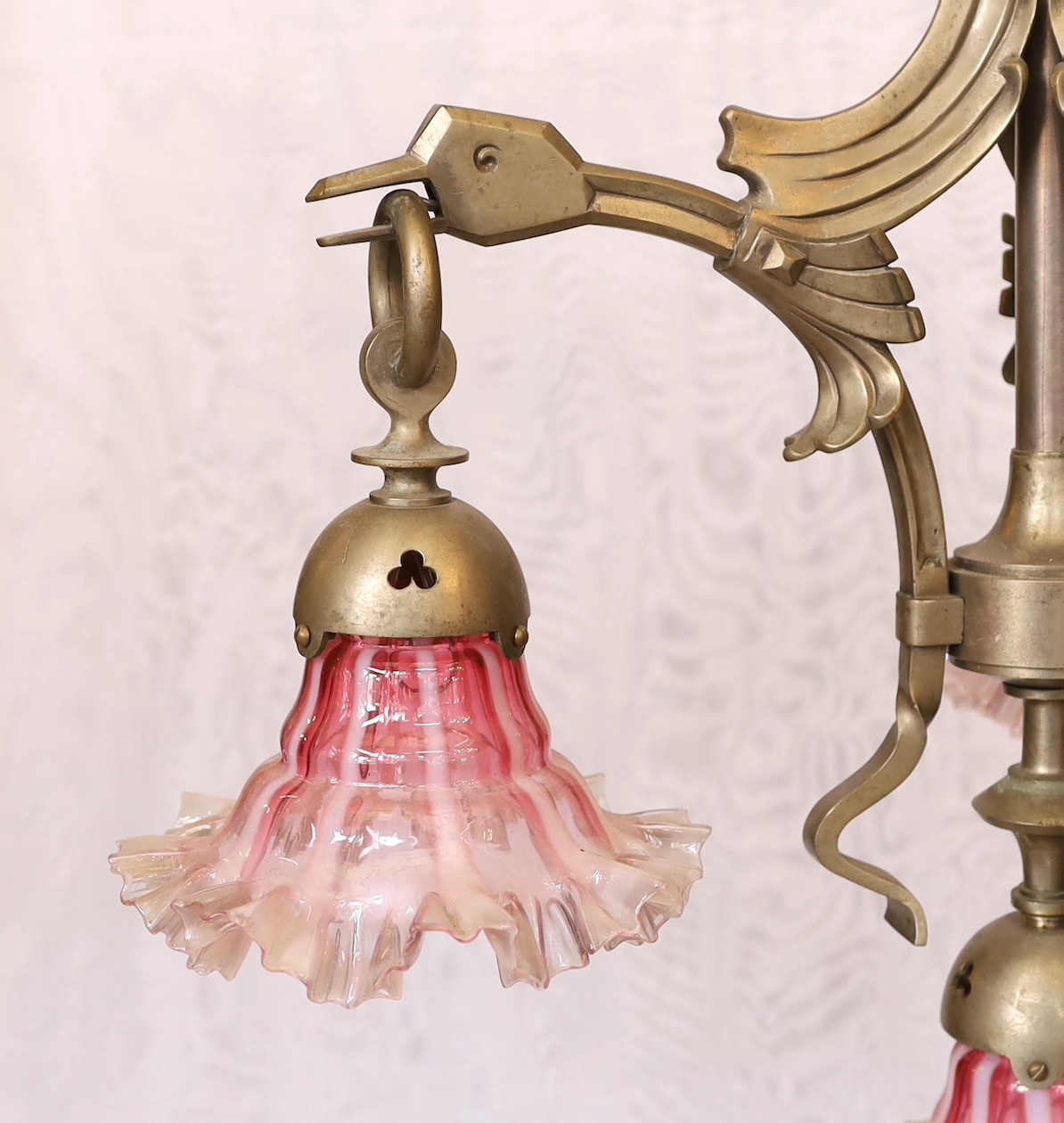 A 1930's Austrian silvered bronze four light chandelier decorated with stylised birds heads, with pink tinted frilled glass shades, height 94cm. width 52cm
